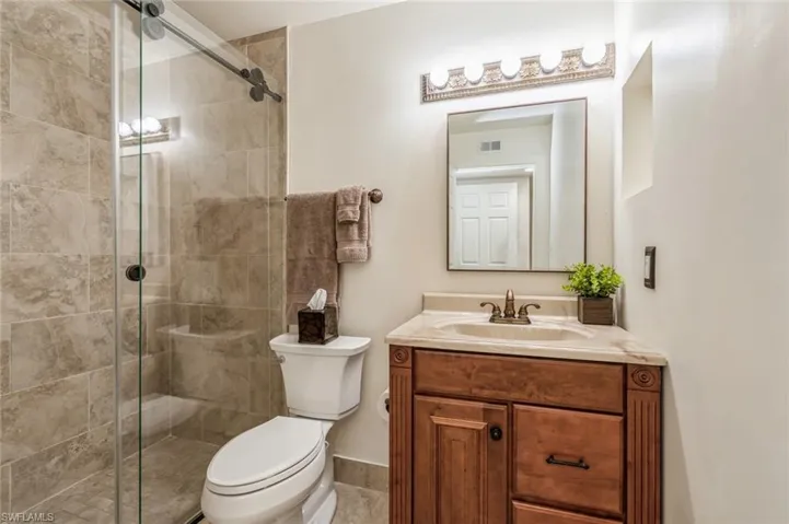 Bathroom with walk in shower, tile flooring, oversized vanity, and toilet