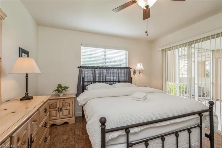 Bedroom with dark hardwood / wood-style flooring, ceiling fan, and multiple windows