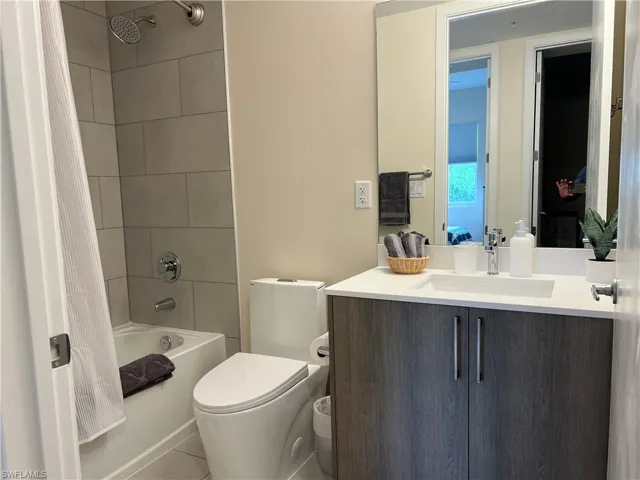 Full bathroom with tile patterned floors, shower / tub combo with curtain, vanity, and toilet