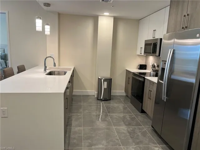 Kitchen with white cabinetry, sink, a kitchen breakfast bar, decorative light fixtures, and appliances with stainless steel finishes