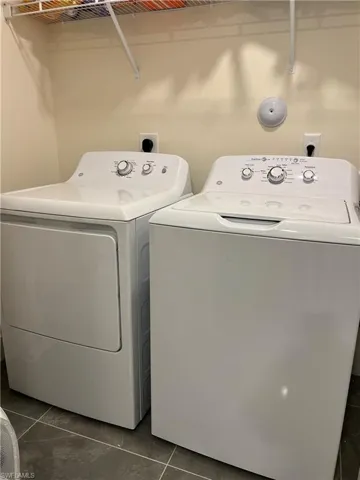 Washroom with separate washer and dryer and dark tile patterned flooring