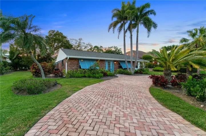 View of front facade featuring a front lawn, decorative driveway, and brick siding