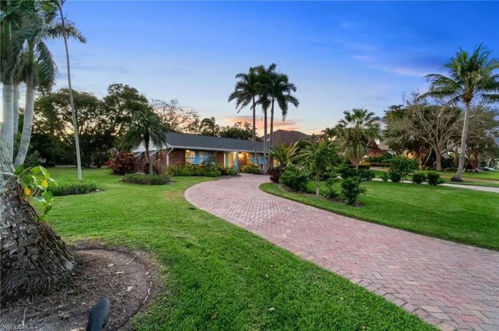 View of front of house featuring a expansive yard, brick exterior, and paver circular driveway