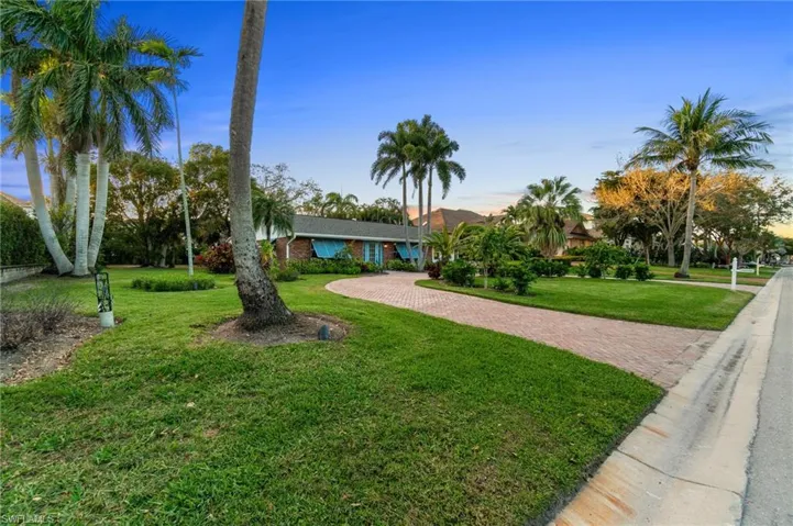 View of front of property with decorative driveway and a front lawn