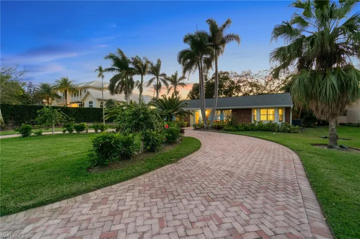 View of front of home with a front yard, decorative paver driveway, and brick siding