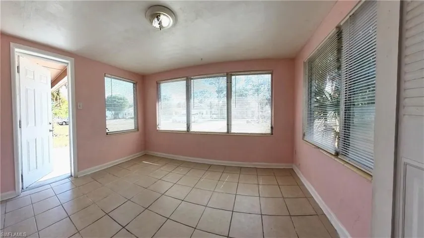 Unfurnished sunroom with tile patterned flooring and baseboards