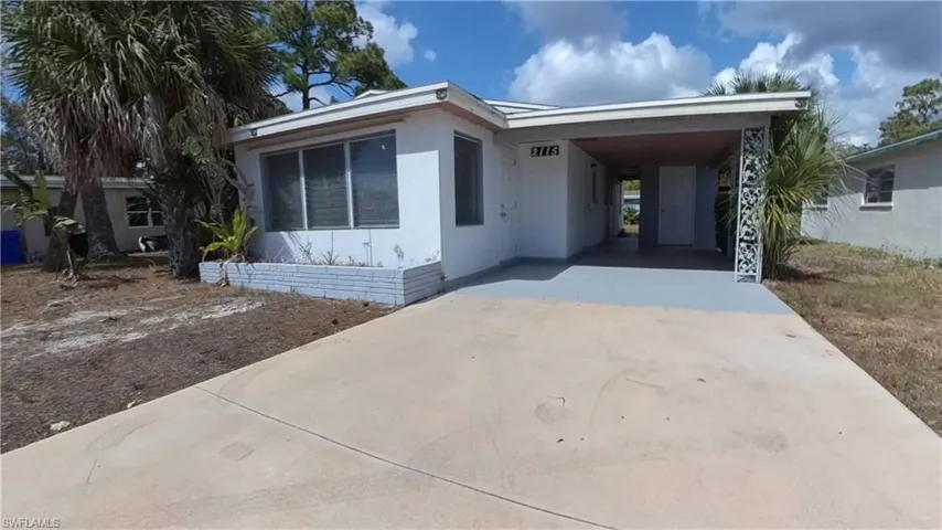 View of front of property featuring concrete driveway, a carport, and a patio