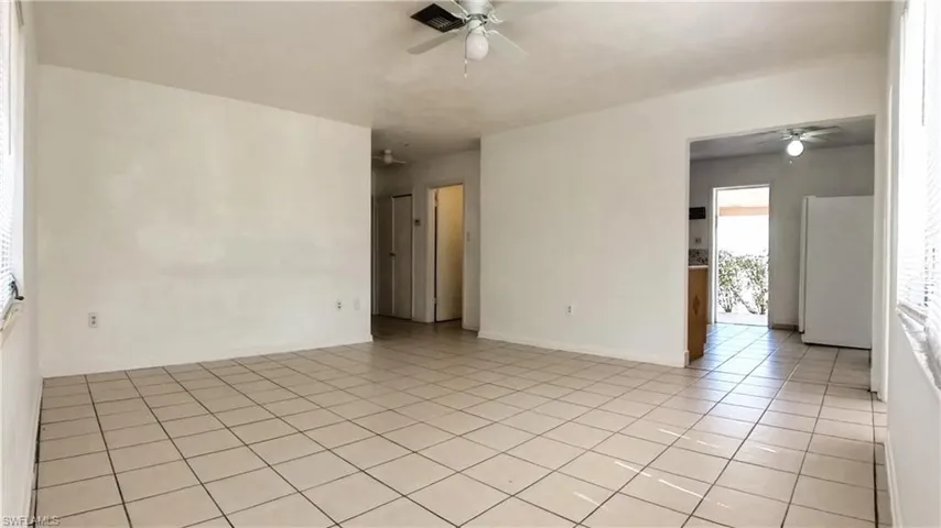 Empty room with ceiling fan and light tile patterned flooring