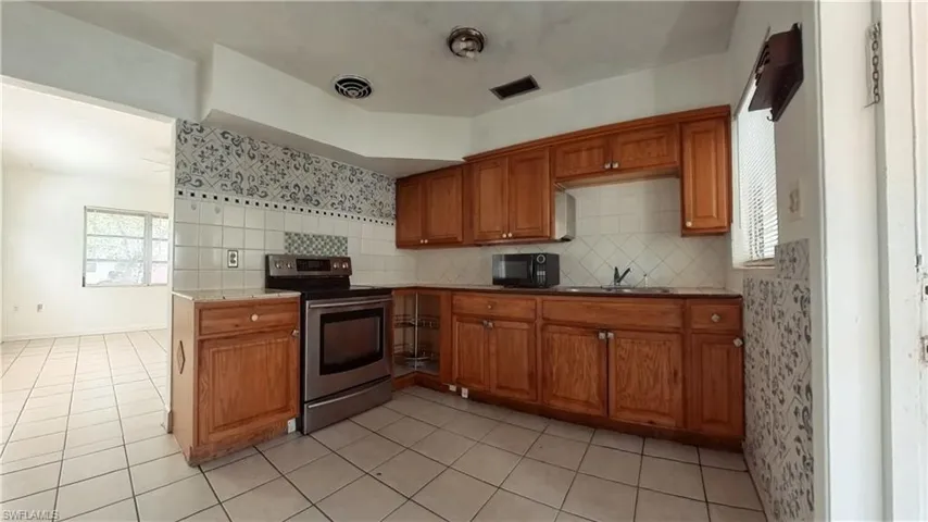 Kitchen featuring wood finish cabinets, stainless steel electric stove, backsplash, and black microwave