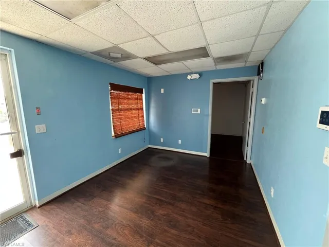 Spacious interior featuring wood-finish flooring, light blue walls, and a dropped ceiling with recessed lighting