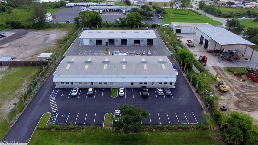 Commercial property featuring two primary buildings, multiple outbuildings, paved parking areas, and perimeter fencing