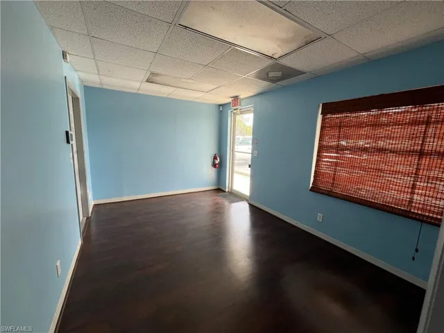 Spacious interior featuring wood-finish flooring, light blue walls, and a dropped ceiling with integrated lighting