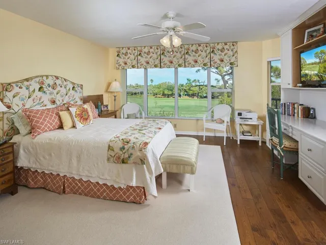 Primary suite with wood floors and expansive windows overlooking golf course