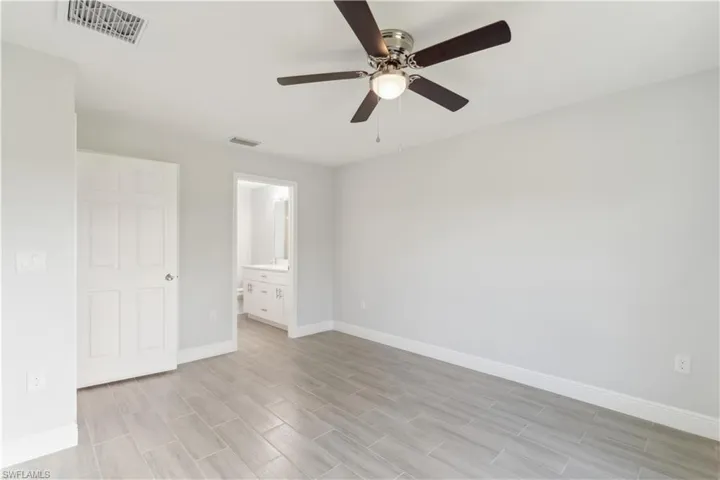 Master bedroom featuring ceiling fan, ensuite bathroom, and light hardwood / wood-style floors