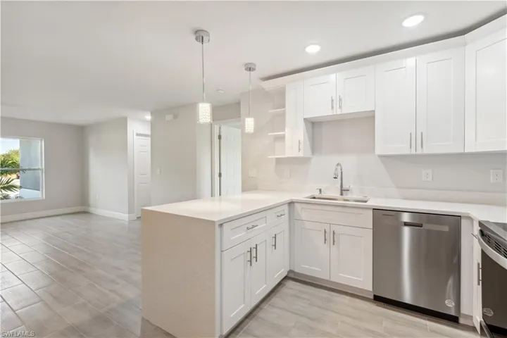 Kitchen with kitchen peninsula, stainless steel appliances, white cabinetry, and sink