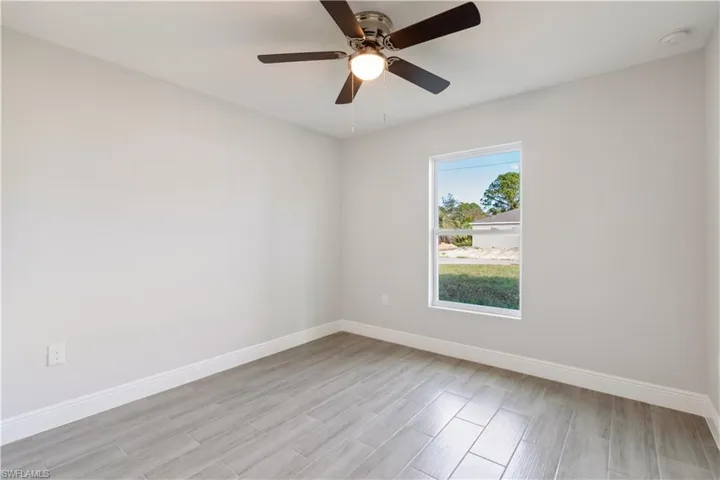 Guest bedroom 1 with light hardwood / wood-style flooring and ceiling fan