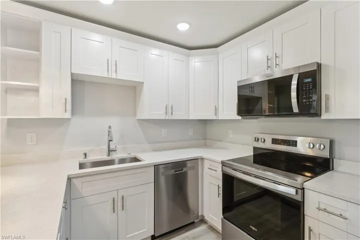 Kitchen featuring white cabinetry, sink, stainless steel appliances, and light quartz counters