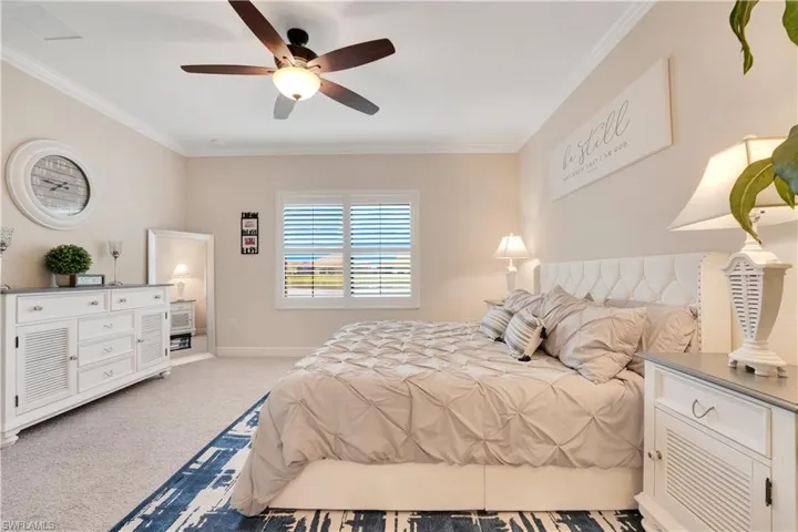 Bedroom featuring light carpet, ceiling fan, baseboards, and crown molding