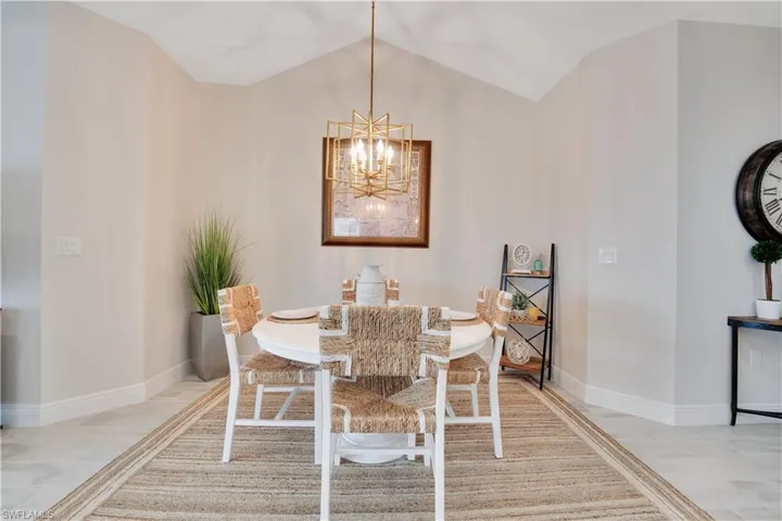 Dining area with a chandelier, light wood-type flooring, vaulted ceiling, and baseboards