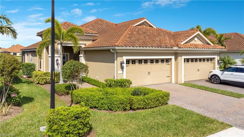 View of front of property with decorative driveway, stucco siding, an attached garage, a front yard, and a tiled roof