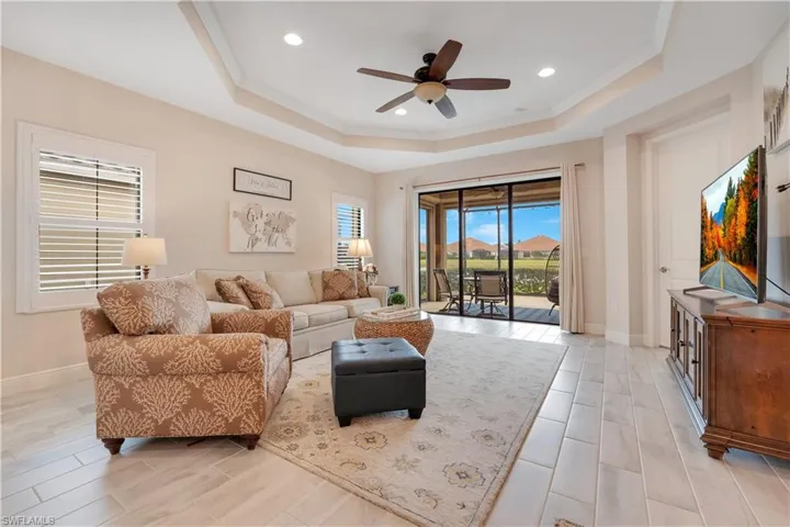 Living area featuring baseboards, a tray ceiling, ceiling fan, and crown molding