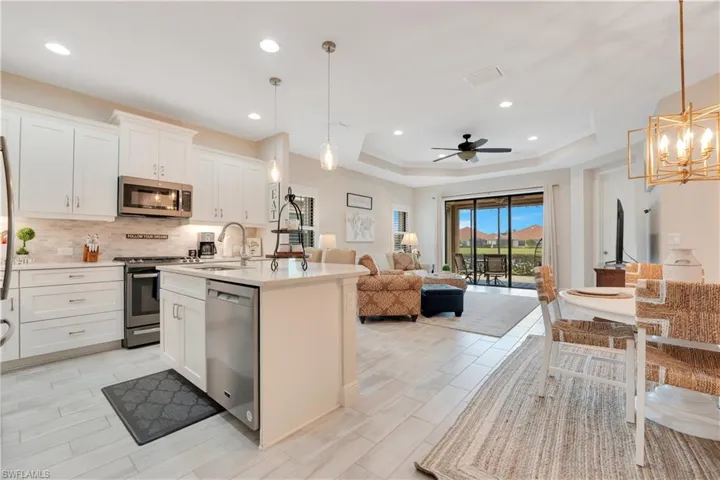 Kitchen with white cabinets, appliances with stainless steel finishes, light countertops, and pendant lighting