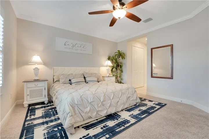 Bedroom with light colored carpet, a closet, visible vents, and crown molding