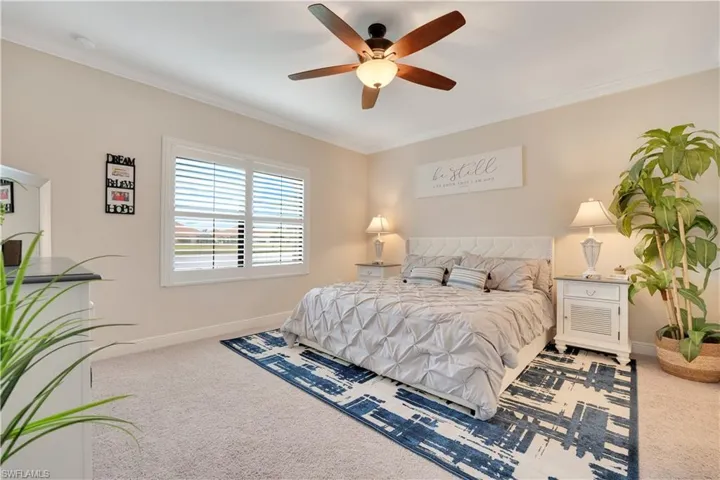 Bedroom with carpet floors, ornamental molding, baseboards, and a ceiling fan