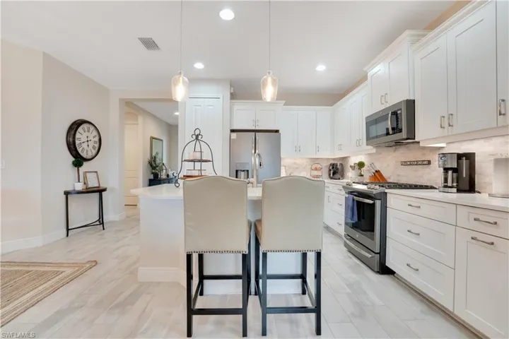 Kitchen with white cabinetry, a center island with sink, appliances with stainless steel finishes, and light countertops
