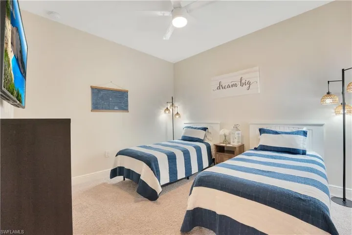 Carpeted bedroom featuring ceiling fan and baseboards