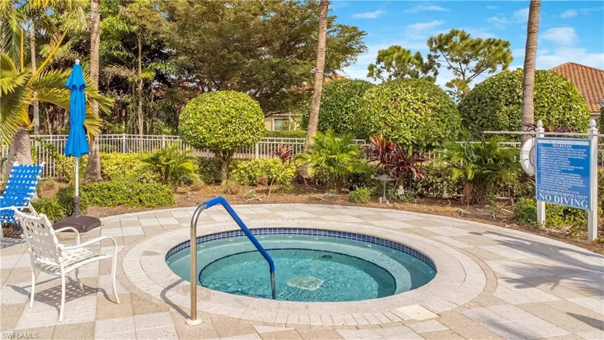 View of swimming pool with fence and a community hot tub