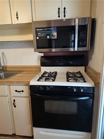 Kitchen featuring light wood-style flooring, white cabinets, ceiling fan, open shelves, and range