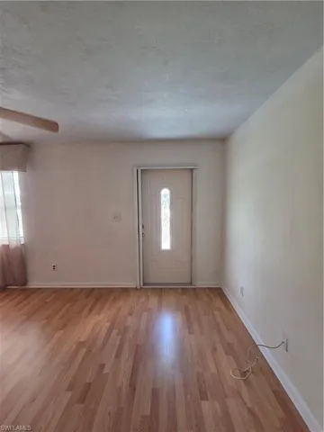 Empty room with wood finished floors, a chandelier, and a ceiling fan