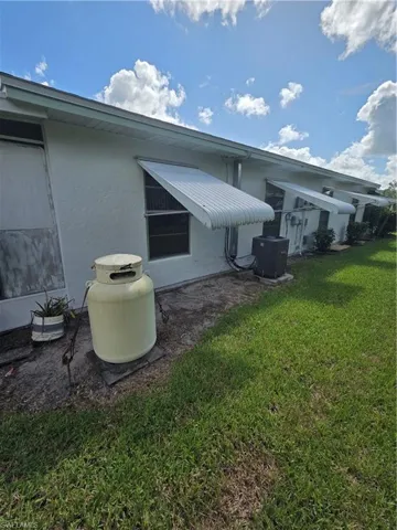 Back of property with a lawn and stucco siding