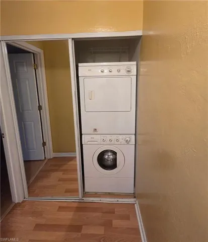 Laundry room with estacked washer and dryer and wood finished floors