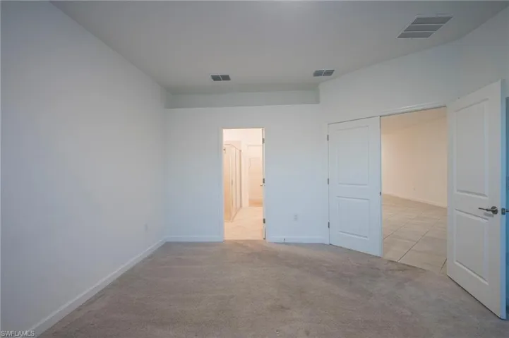 Unfurnished bedroom featuring light colored carpet and light tile patterned flooring