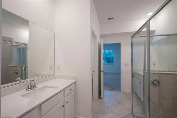 Full bathroom with vanity, a stall shower, and light tile patterned floors