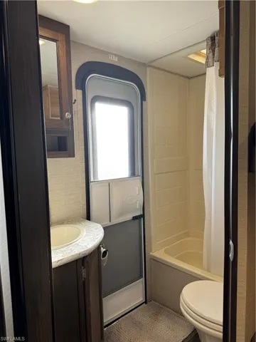 Full bathroom with shower / bath combo, vanity, and toilet