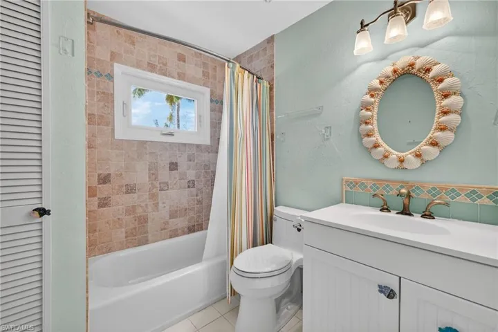 Bathroom featuring vanity, shower / tub combo, a closet, a textured wall, and light tile patterned floors