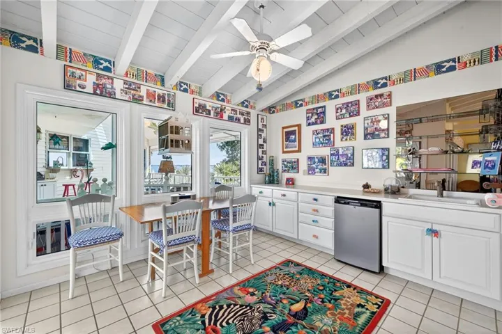 Kitchen featuring white cabinets, a ceiling fan, stainless steel dishwasher, light countertops, and light tile patterned flooring