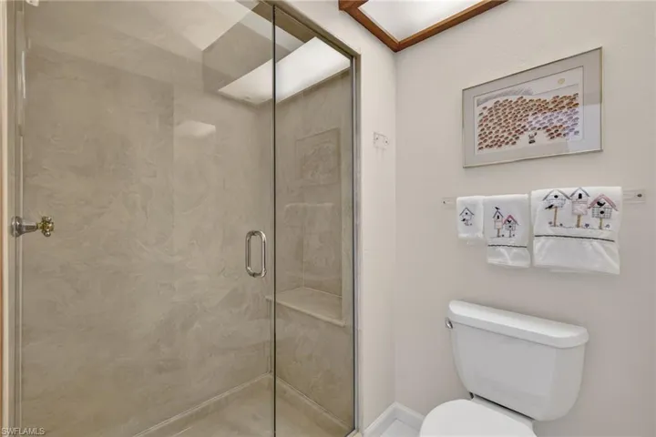 Full bathroom featuring a marble finish shower and toilet