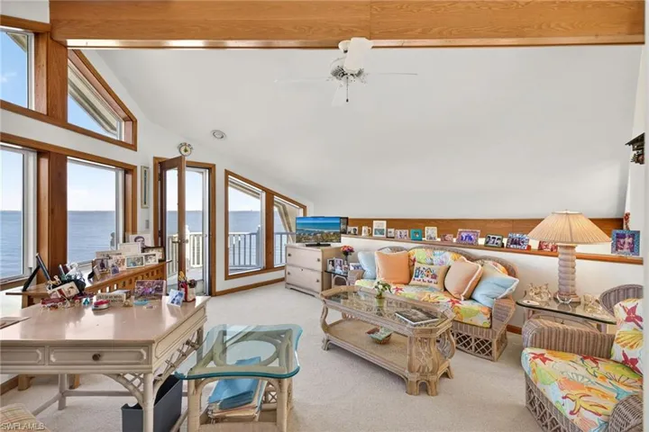Loft/Den area featuring high vaulted ceiling, light colored carpet, and ceiling fan