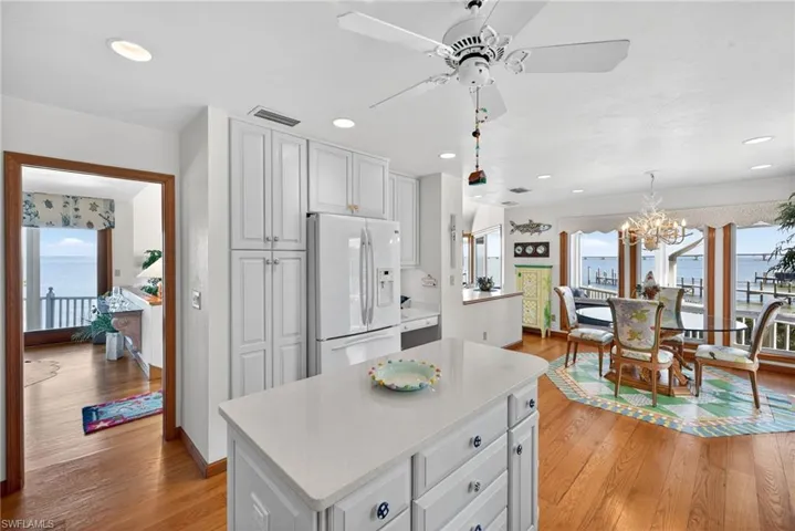 Kitchen with plenty of natural light, white refrigerator with ice dispenser, white cabinetry, and recessed lighting