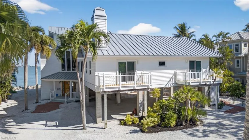 Front of property featuring a patio, a metal roof, a standing seam roof, a water view, and a chimney