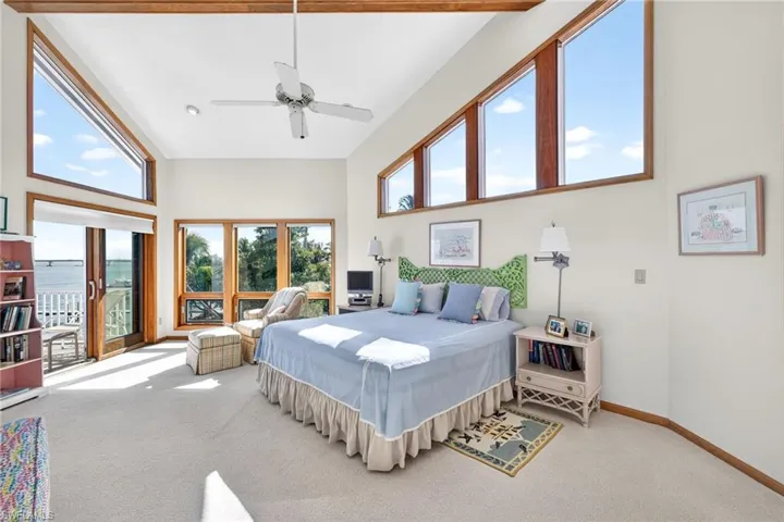 Carpeted bedroom with a high ceiling and a ceiling fan
