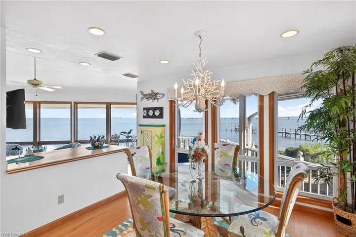 Dining area featuring a water view, a chandelier, plenty of natural light, light wood-style flooring, and recessed lighting