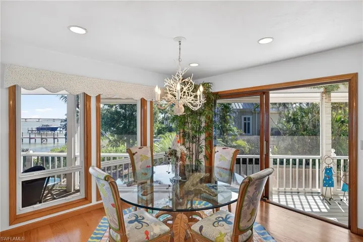 Dining room with a water view, wood finished floors, a chandelier, and recessed lighting
