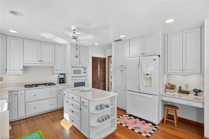 Kitchen with open shelves, white appliances, white cabinets, a center island, and light wood finished floors