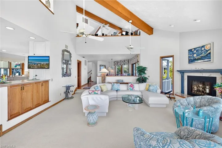 Living area with light carpet, recessed lighting, high vaulted ceiling, ceiling fan, and a fireplace