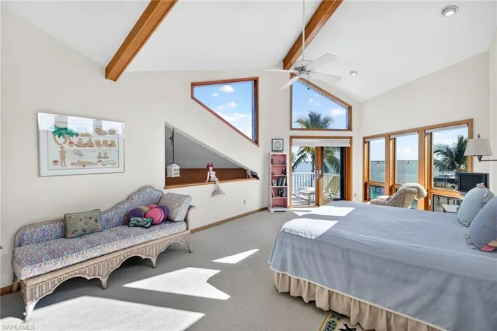 Carpeted bedroom with high vaulted ceiling, beam ceiling, ceiling fan, multiple windows, and access to outside